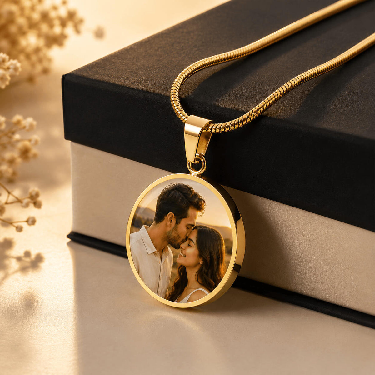 Gold personalized circle photo necklace with couple portrait displayed beside gift box