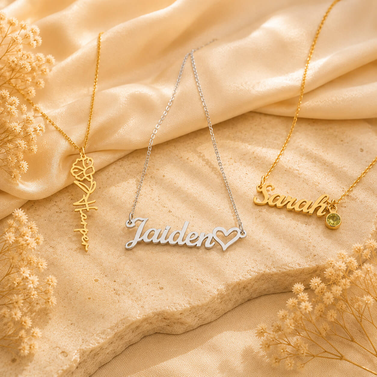 Personalized name necklaces in gold and silver displayed on a soft cream background