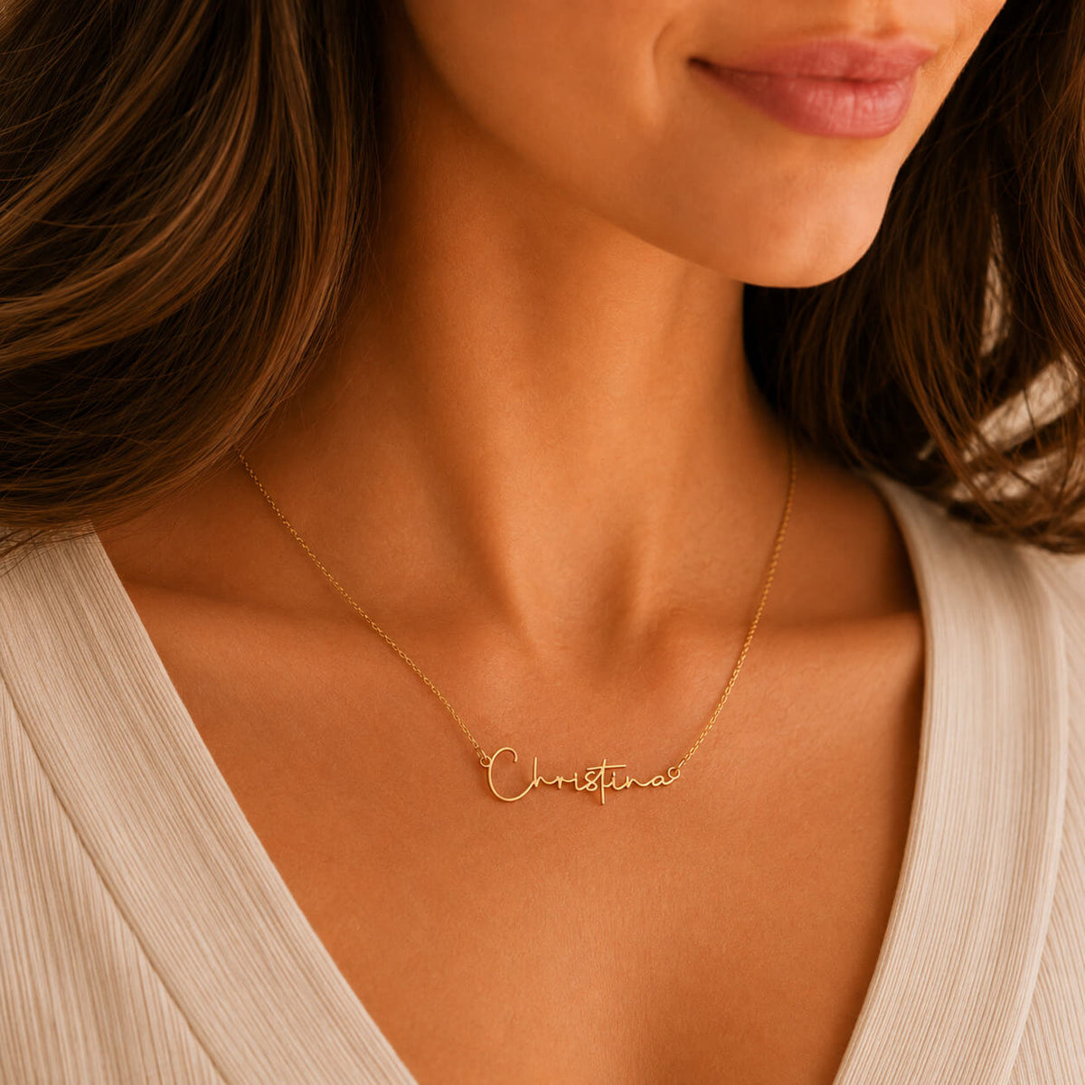 Close-up of personalized signature name necklace in gold worn by a woman