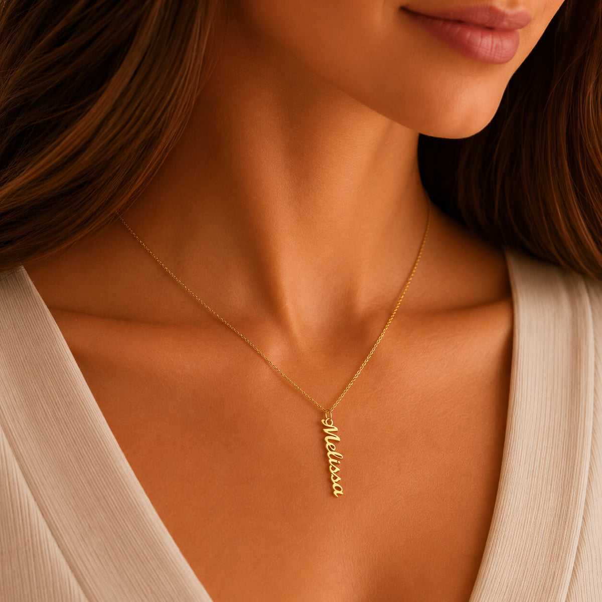 Close-up of personalized vertical name necklace in gold worn by a woman