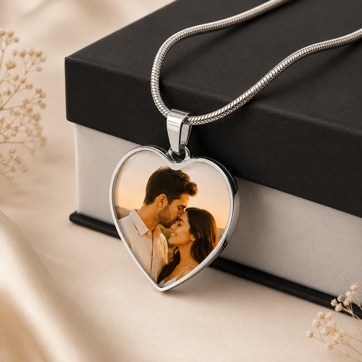Silver personalized heart photo necklace with couple portrait displayed beside gift box