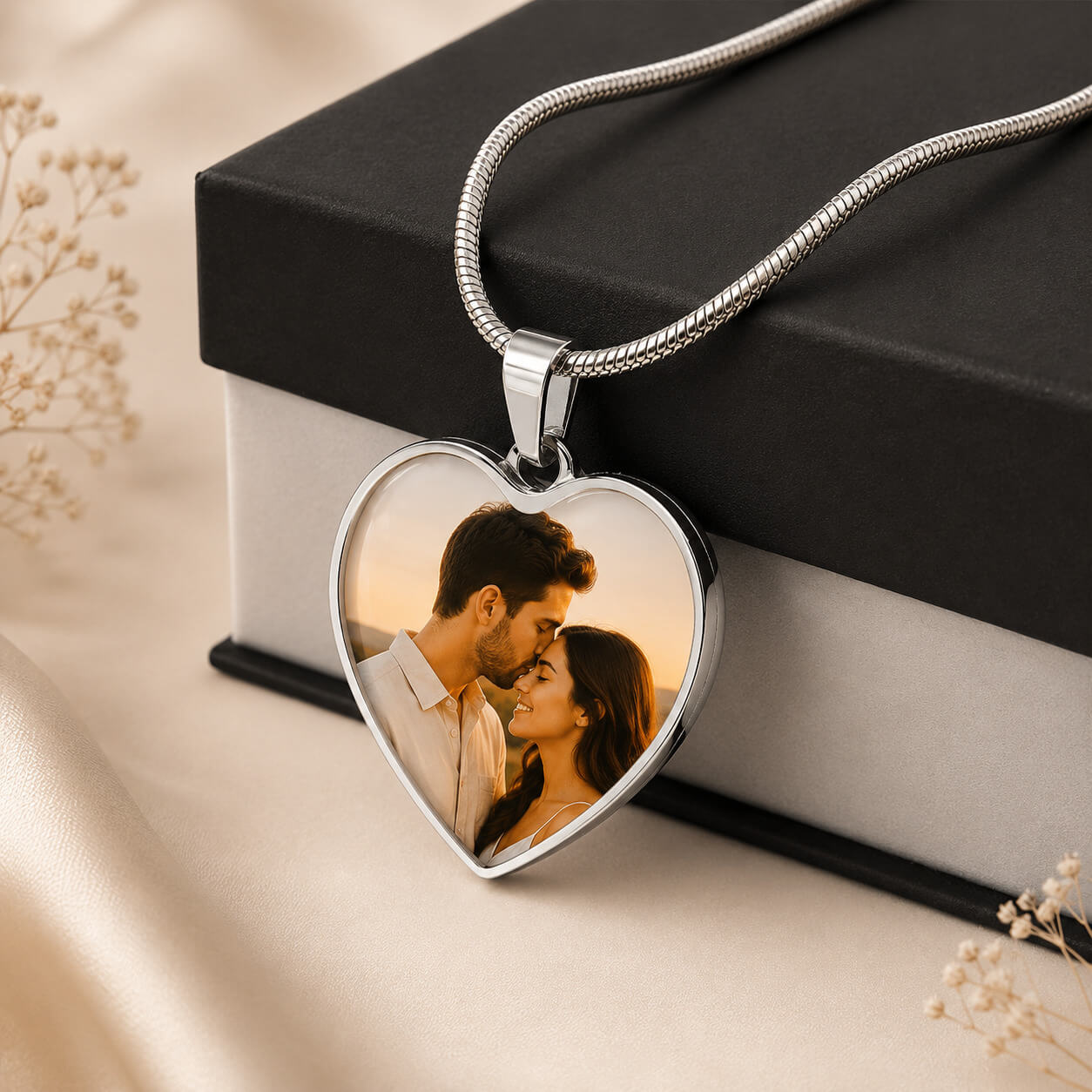 Silver personalized heart photo necklace with couple portrait displayed beside gift box